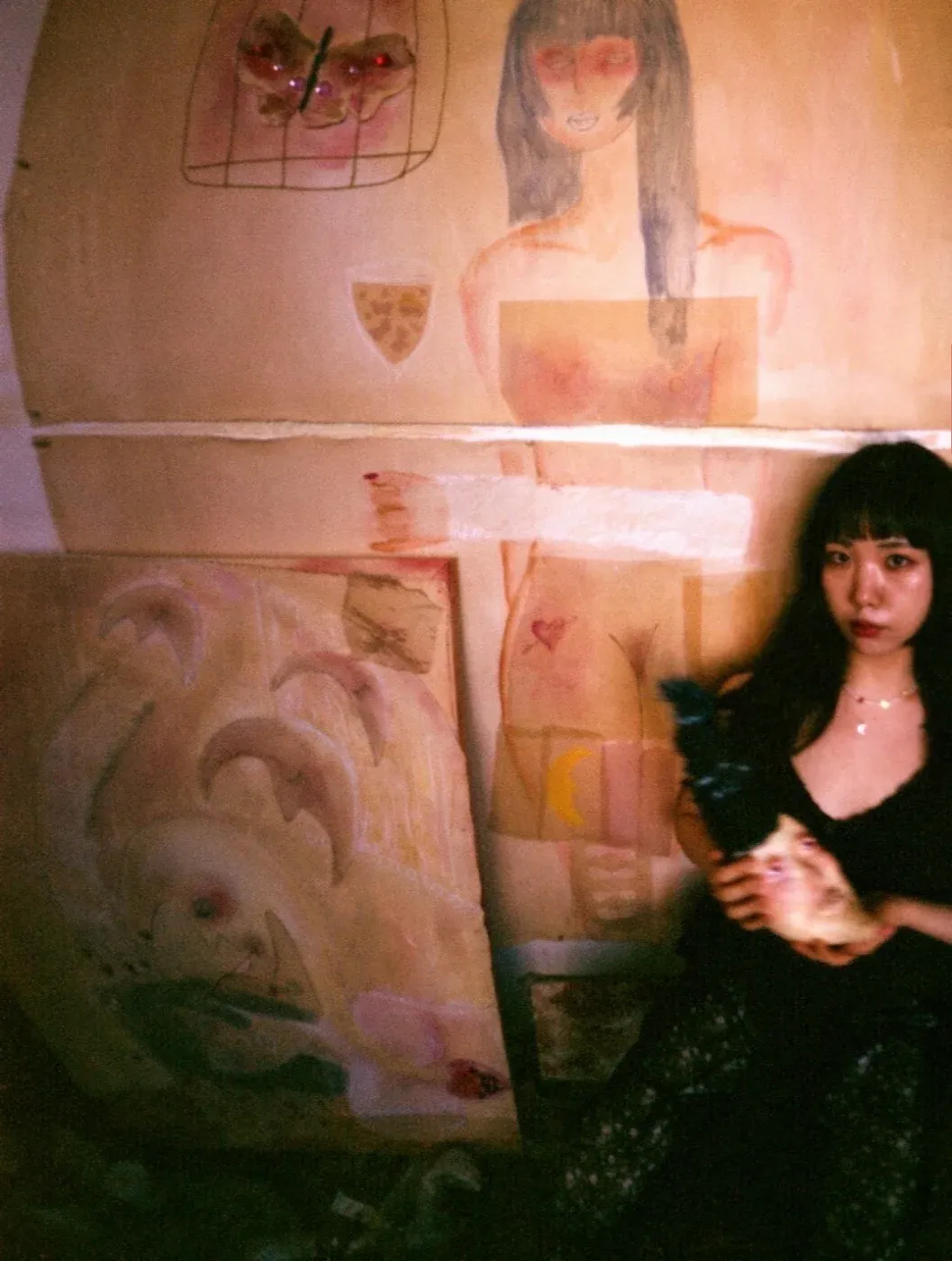 Portrait of artist Ailyn Lee in her studio with pastel canvases; abstract body fragments and symbols in soft light reflect her series ‘Alchemy of Memory—Bodies, Objects, Transformation’.