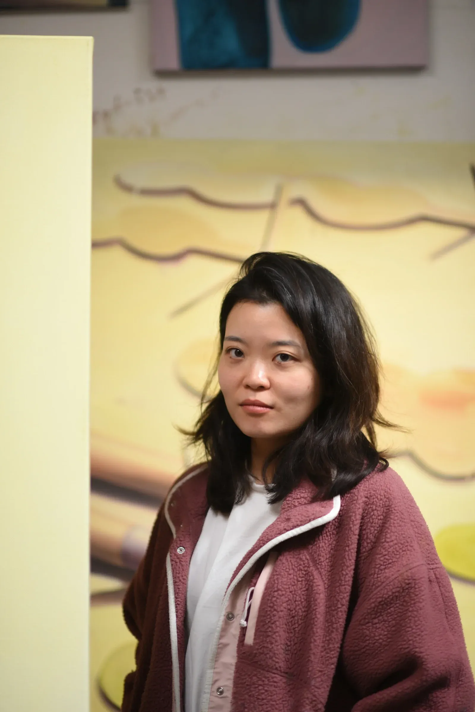 Portrait of contemporary painter Jeehye Song in front of her artwork, professional artist photo.