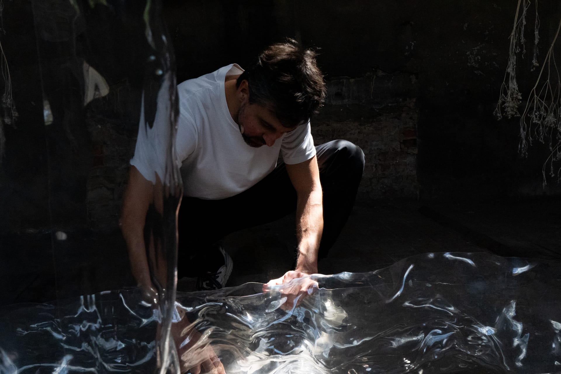 Luca Vanello working with translucent material in a dark installation space, focusing on texture, light, and tactile engagement, photographed by Stephen Kyndt