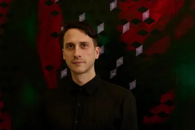 Matthias Esch, Berlin-based painter, portrait in front of a red-green geometric cube grid painting; contemporary abstraction about systems, structure and ornament; studio view.