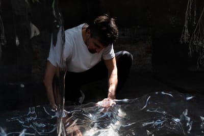 Luca Vanello working with translucent material in a dark installation space, focusing on texture, light, and tactile engagement, photographed by Stephen Kyndt